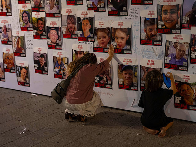 A woman touches photos of Israelis missing and held captive in Gaza, displayed on a wall in Tel Aviv, on Saturday, Oct. 21, 2023. One of the missing, Ohad Munder-Zichri, turned 9 on Monday. But instead of celebrating at home with his family and friends, he was somewhere in Gaza, one of more than 200 Israelis held hostage by Hamas since their devastating Oct. 7 incursion. (AP Photo/Petros Giannakouris, File) Hostage