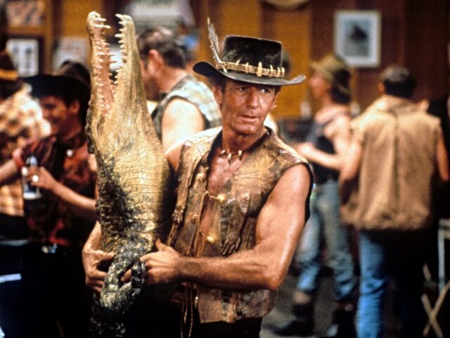 film tariffs Paul Hogan carrying dead crocodile in bar in a scene from the film 'Crocodile Dundee', 198