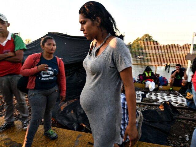 A Honduran pregnant woman taking part in a caravan heading to the US, waits to cross the b