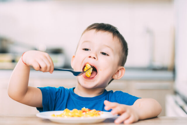 gettyimages-1160049332-640x427-1 a child in a t-shirt in the kitchen eating an omelet, a fork