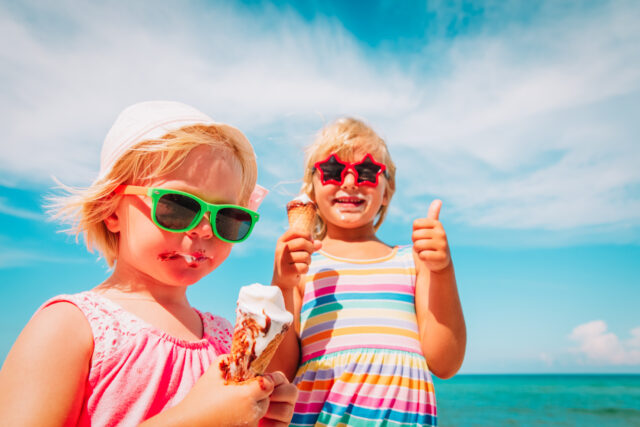 happy cute little girls eating ice cream on beach happy cute little girls eating ice cream on beach vacation