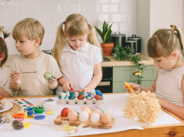 Kids painting eggs for Easter Kids painting eggs and Easter bread in the kitchen
