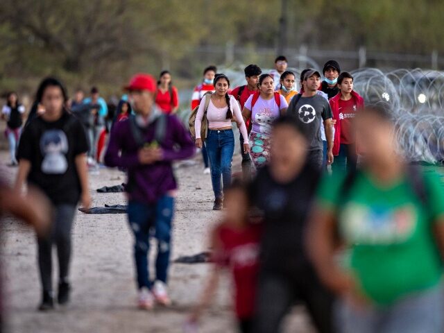 Surge Of Migrants Overwhelms Border Crossings EAGLE PASS, TEXAS - DECEMBER 17: Migrants walk towards a field processing center after cro