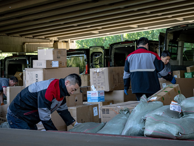 GettyImages-2211998397 Workers sort packages in front of SF Express vans, operated by SF Holding Co., in Beijing,
