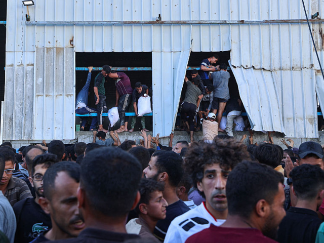 GettyImages-2216874392 Displaced Palestinians ferry bags of food aid after storming a World Food Programme wareho