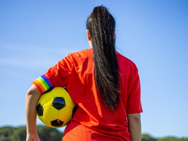trans athlete Soccer player woman with a soccer ball and captain armband with the LGBT pride flag on the