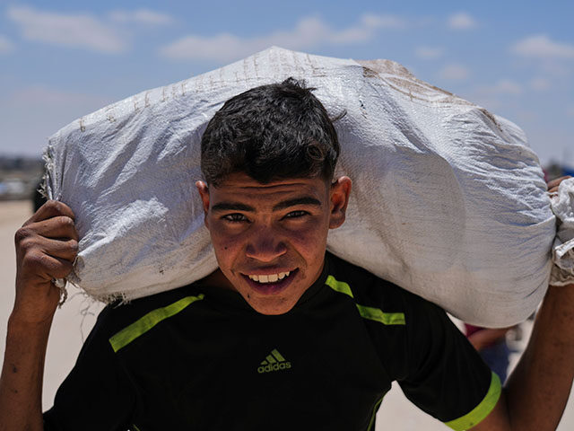A Palestinian youth carries food and humanitarian aid delivered by the U.S.-backed Gaza Hu