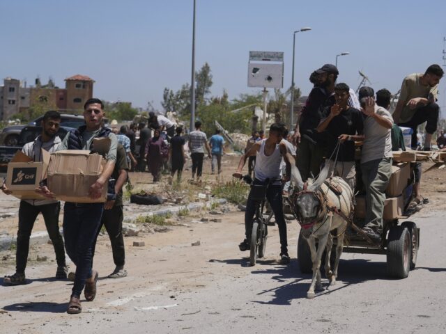 Gaza GHF (Abdel Kareem Hana / Associated Press) Palestinians carry boxes and bags containing food and humanitarian aid packages delivered