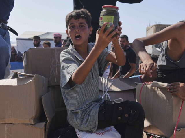 Palestinians carry boxes containing food and humanitarian aid packages delivered by the Ga