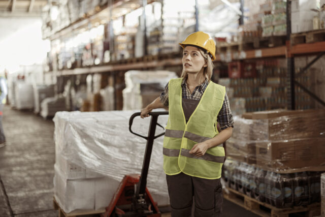 Getting orders on the move Female warehouse manager pulling a pallet truck