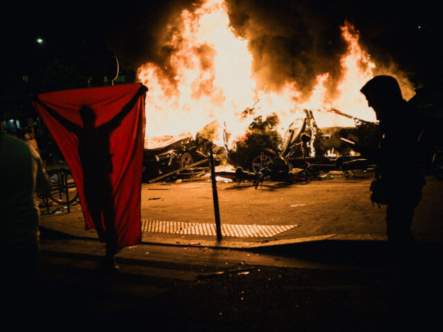gettyimages-2217425212-1-640x480-1 A person with a flag in front of two cars on fire during celebrations on the Place de la P