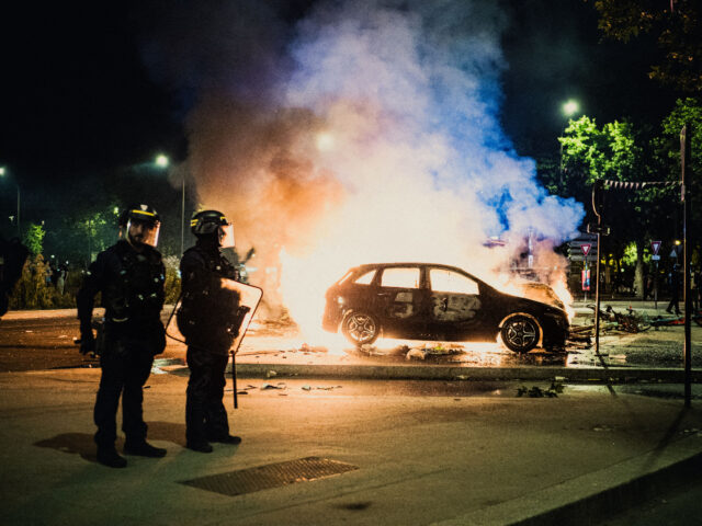 gettyimages-2217459866-1-640x480-1 Police officers stand next to a car on fire during celebrations in the Place de la Porte d