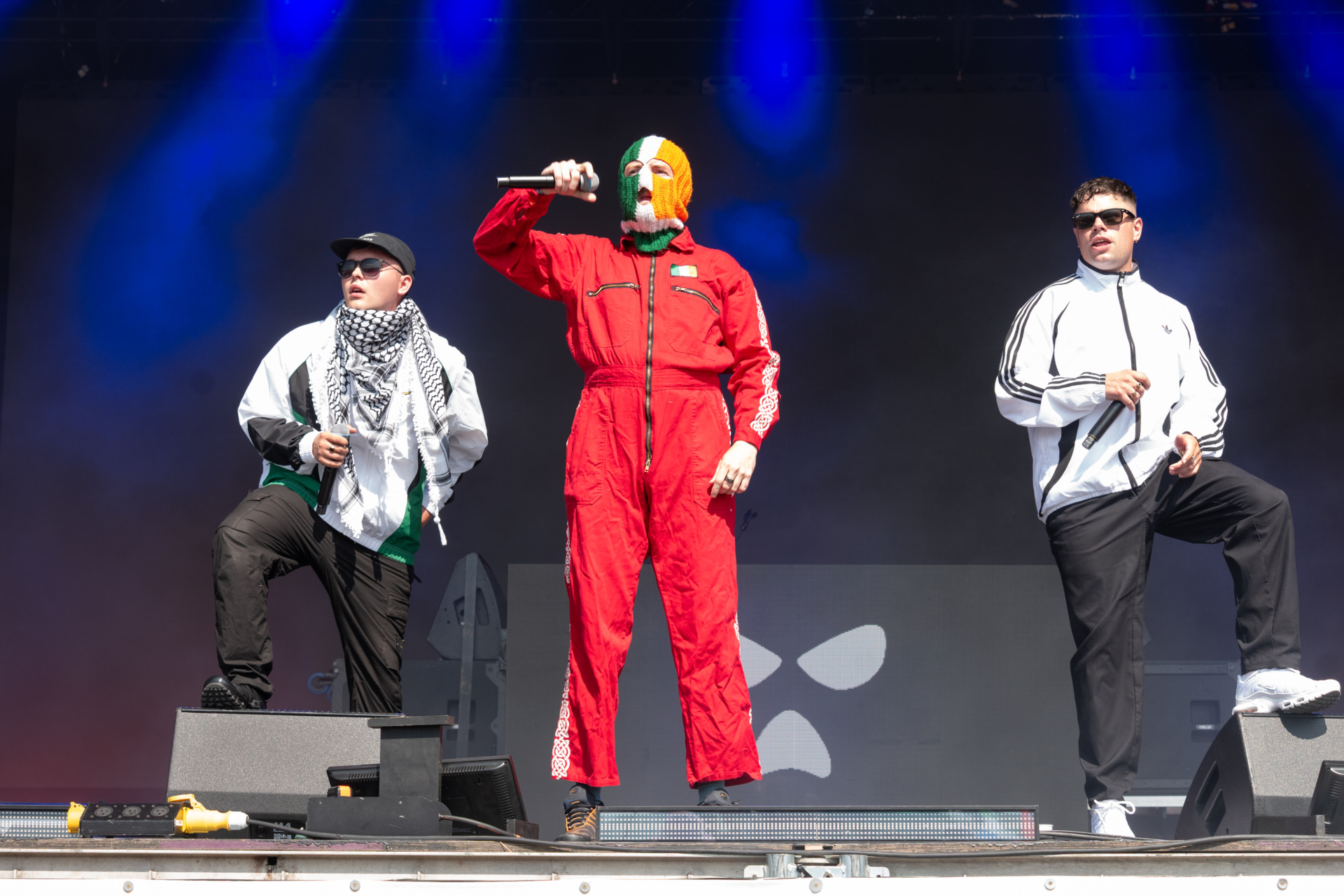 gettyimages-2222636395 GLASTONBURY, ENGLAND - JUNE 28: Mo Chara, DJ Provaí and Móglaí Bap of Kneecap perform on the West Holts stage during day four of Glastonbury festival 2025 at Worthy Farm, Pilton on June 28, 2025 in Glastonbury, England. Established by Michael Eavis in 1970, Glastonbury has grown into the UK's largest music festival, drawing over 200,000 fans to enjoy performances across more than 100 stages. In 2026, the festival will take a fallow year, a planned pause to allow the Worthy Farm site time to rest and recover. (Photo by Ki Price/WireImage)