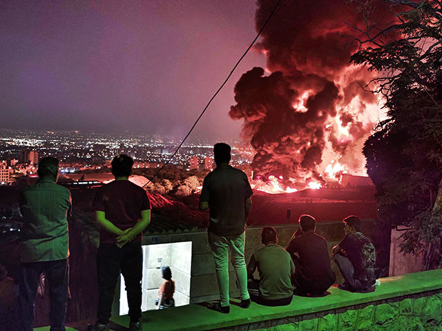 gettyimages2219495862-640x480-1 People observe fire and smoke from an Israeli attack on the Shahran oil depot on June 15,