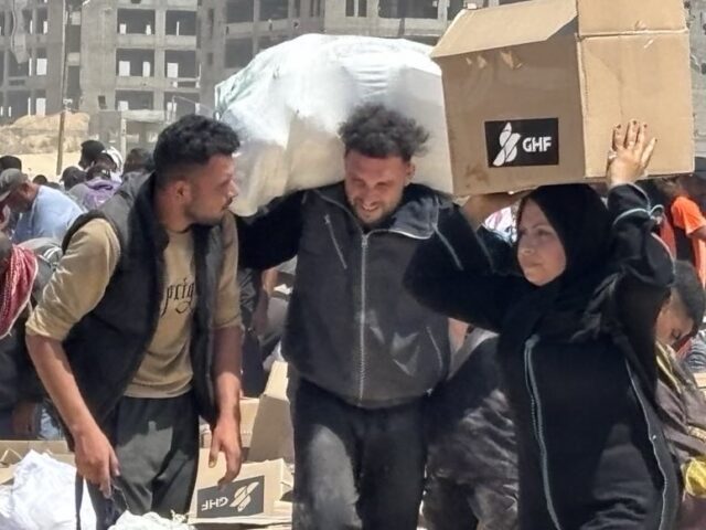 Palestinians at GHF (Courtesy Gaza Humanitarian Foundation) Palestinians collect aid boxes at an aid site run by the U.S.-backed Gaza Humanitarian Fou