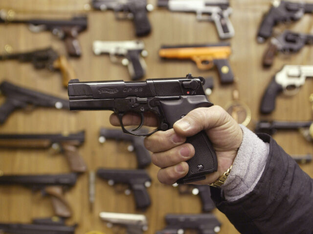 Man Tries Out a Gun A man holds an Airsoft plastic BB gun in front of a shop display of the hobbyist replica f