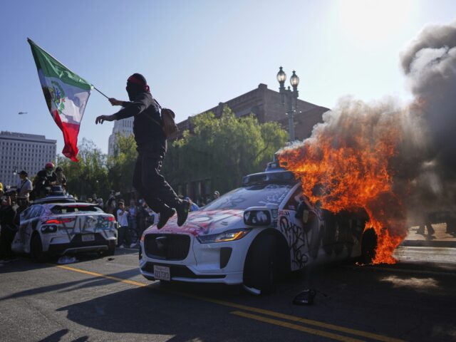 Mexican fire flag ICE riots Los Angeles (Eric Thayer / Associated Press) A protester leaps off a burning Waymo taxi near the Metropolitan Detention Center in downt