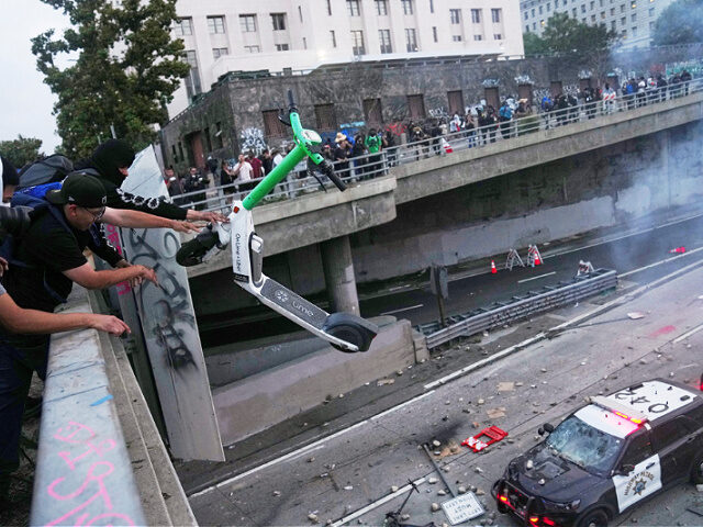 protester-throws-scooter-police-June8-25-los-angeles-ap A protester throws a scooter at a police vehical near the metropolitan detention center of