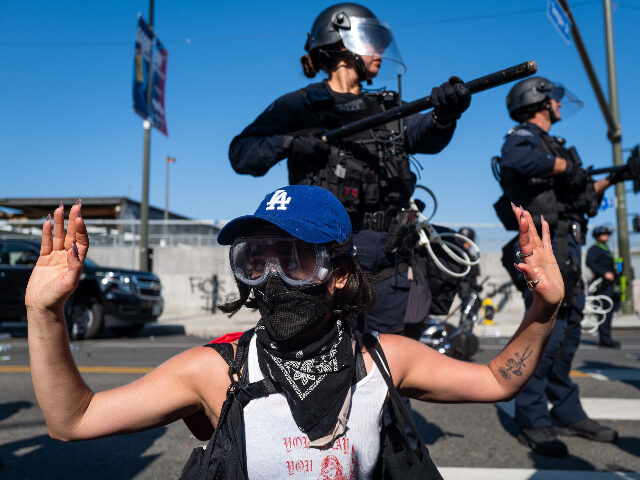 riotshollywood LOS ANGELES, CALIFORNIA - JUNE 08: A protester raises their hands in front of LAPD officer