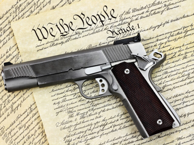 Handgun lying over a copy of the United States constitution with the words "We the Pe