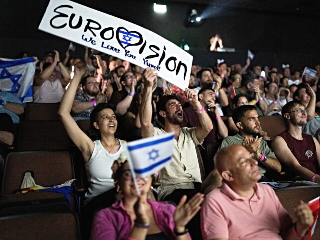 People cheer as they watch the 2025 Eurovision Song Contest finals being screened at a com