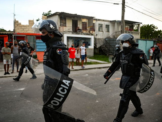 Riot police walk the streets after a demonstration against the government of President Mig