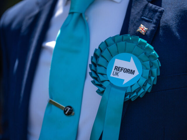 gettyimages-2158466198-1-640x480-1 MAIDSTONE, ENGLAND - JUNE 24: A supporter wears a Reform UK rosette before a campaign spee