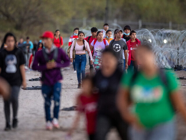 Migrants Migrants walk towards a field processing center after crossing from Mexico into the United
